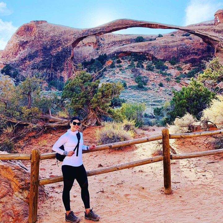 This is a picture taken of Sylvia standing next to a wooden fence located at Arches National Park in Utah.